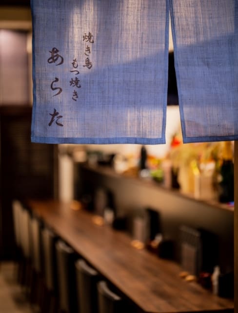「焼き鳥 もつ焼き あらた」と書かれた藍色の暖簾